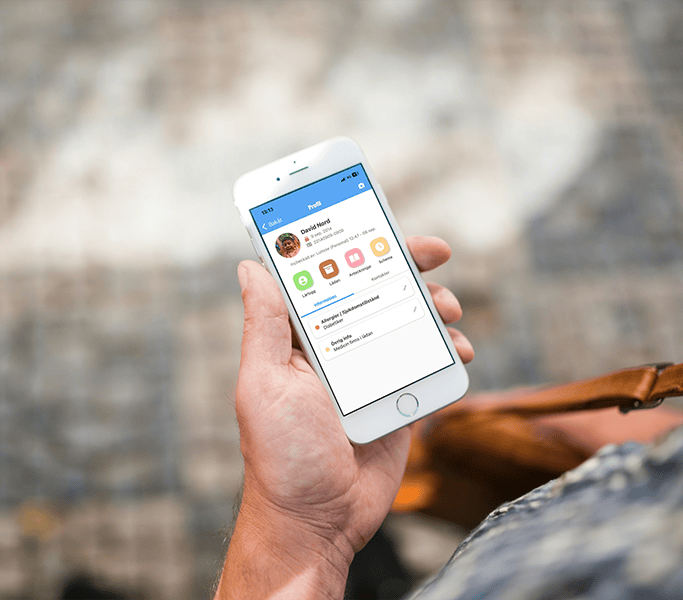 Hand holding a smartphone showing a child's profile screen in the TYRA app